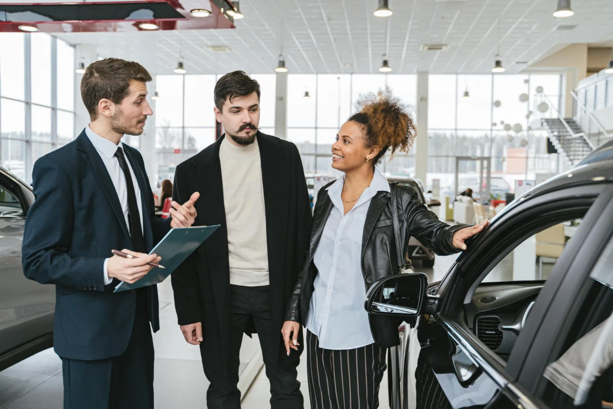 Family reviewing a vehicle with a dealership advisor while shopping for a family car in Canada with Value Car Deals