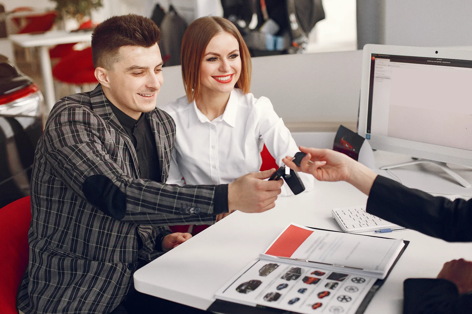 Customers reviewing vehicle pricing and receiving car keys at Value Car Deals serving the Lower Mainland region of Canada