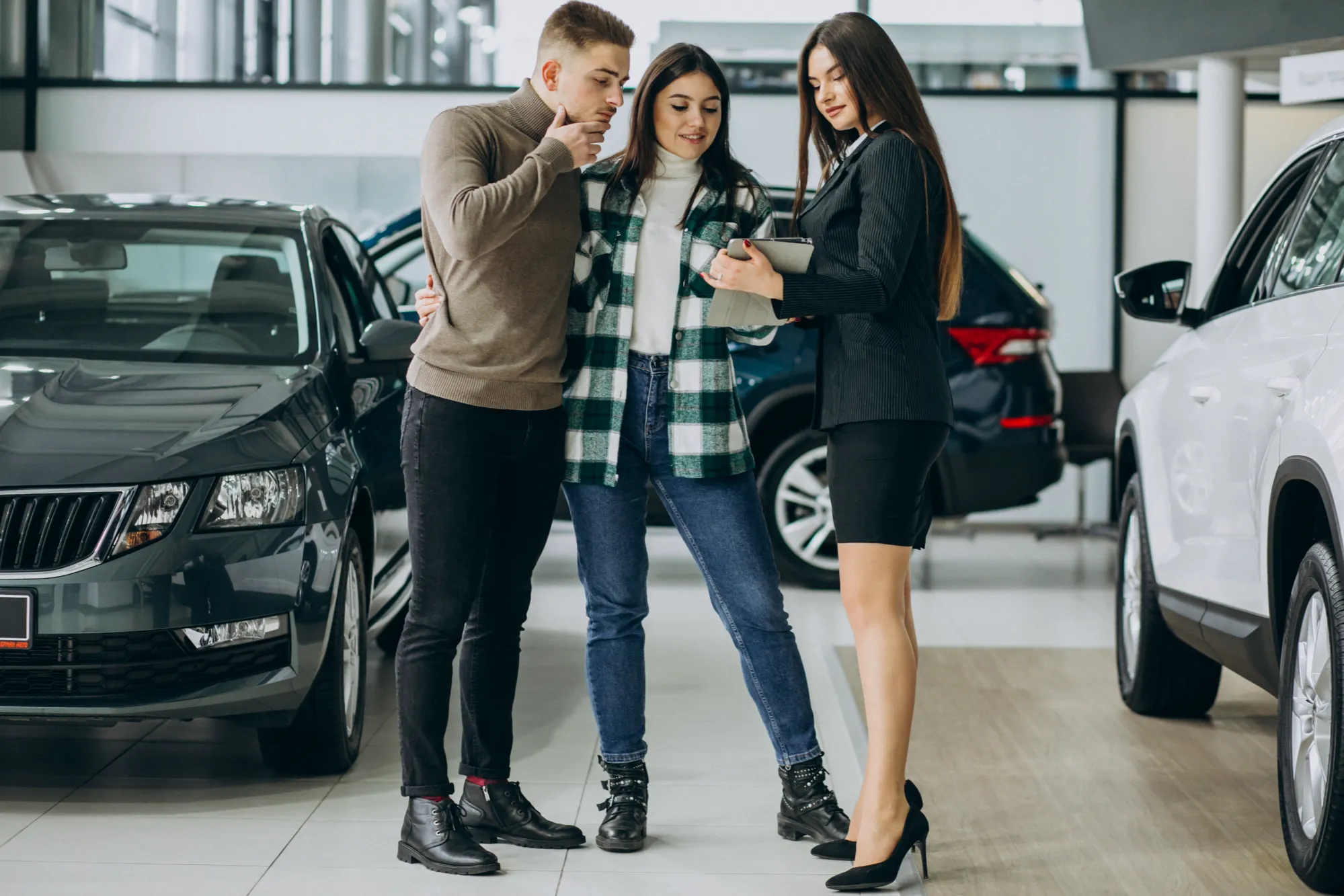 Car shoppers learning about electric vehicles at a dealership in Canada with guidance from Value Car Deals