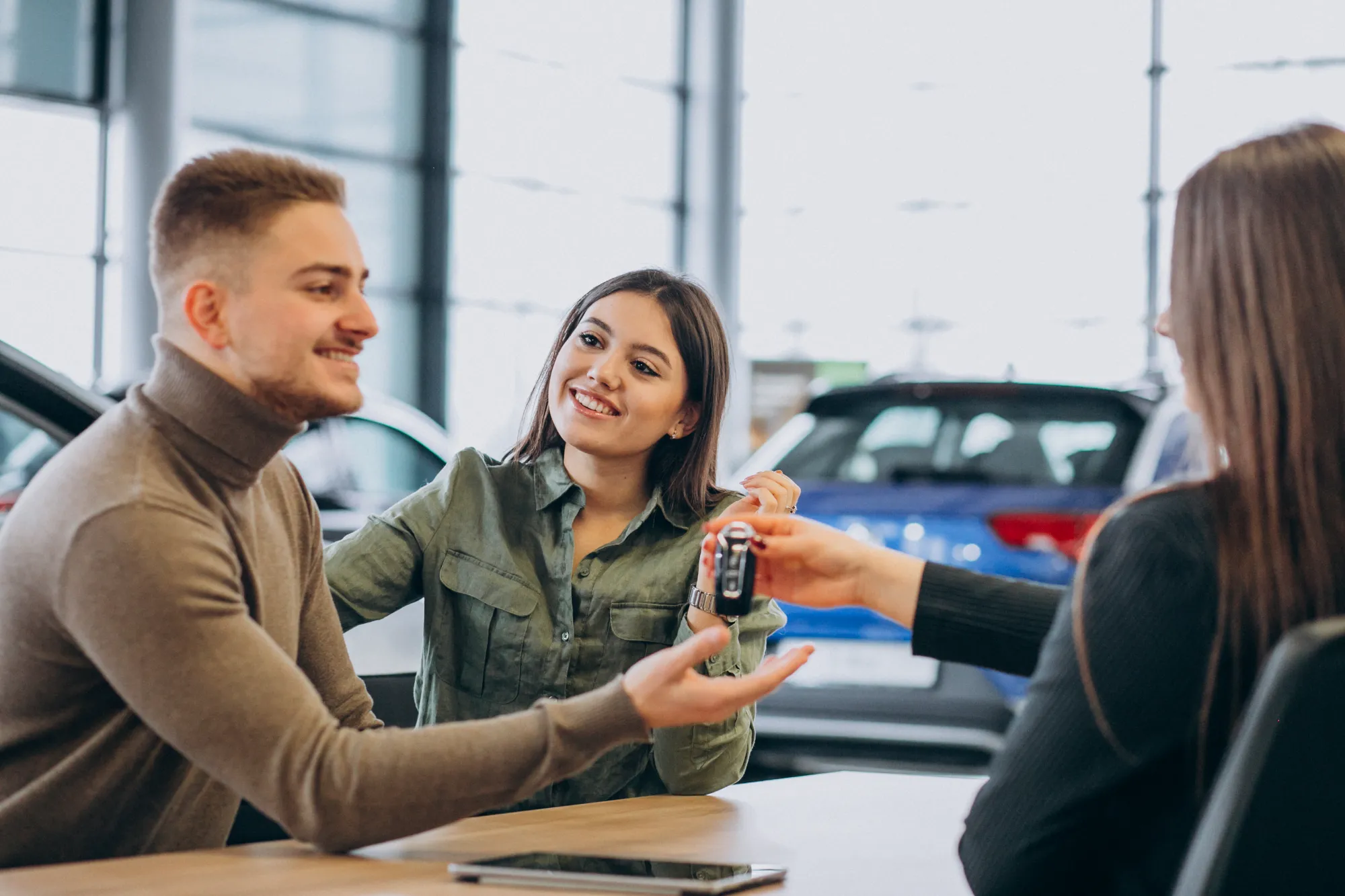 Auto leasing advisor handing vehicle keys to customers at Value Car Deals serving the Lower Mainland region of Canada