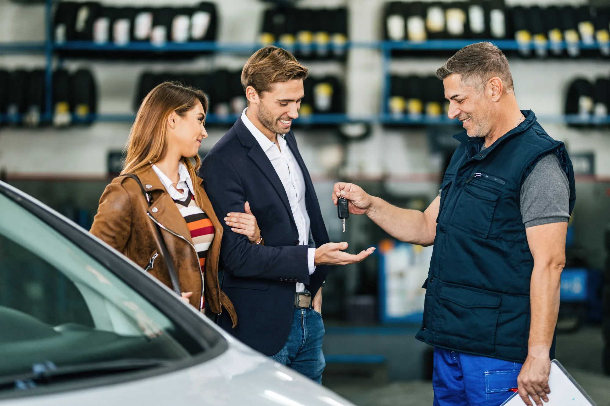 Couple receiving car keys while buying a used vehicle at a dealership in Canada with Value Car Deals